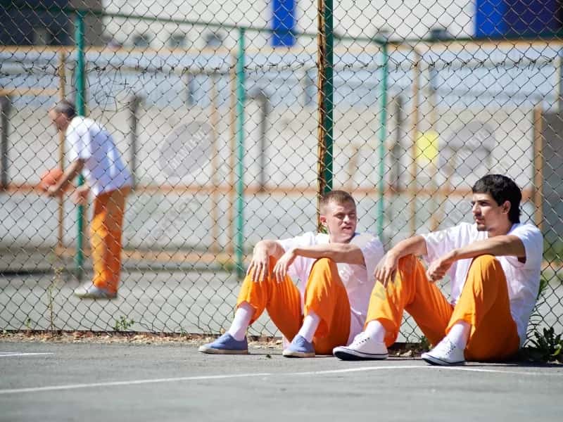2men_prisoners_outdoors_fence_sitting_seated_orange_pants_2008_2600x1950.jpg.jpg